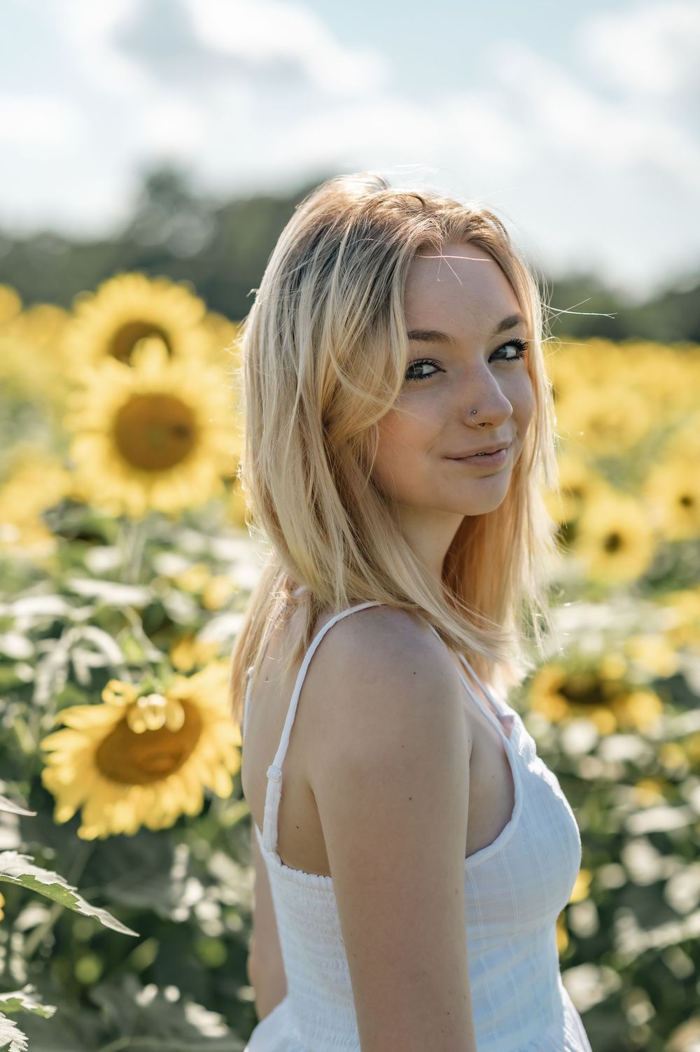 Portrait in sunflower field with bright yellow blooms on sunny summer day.
