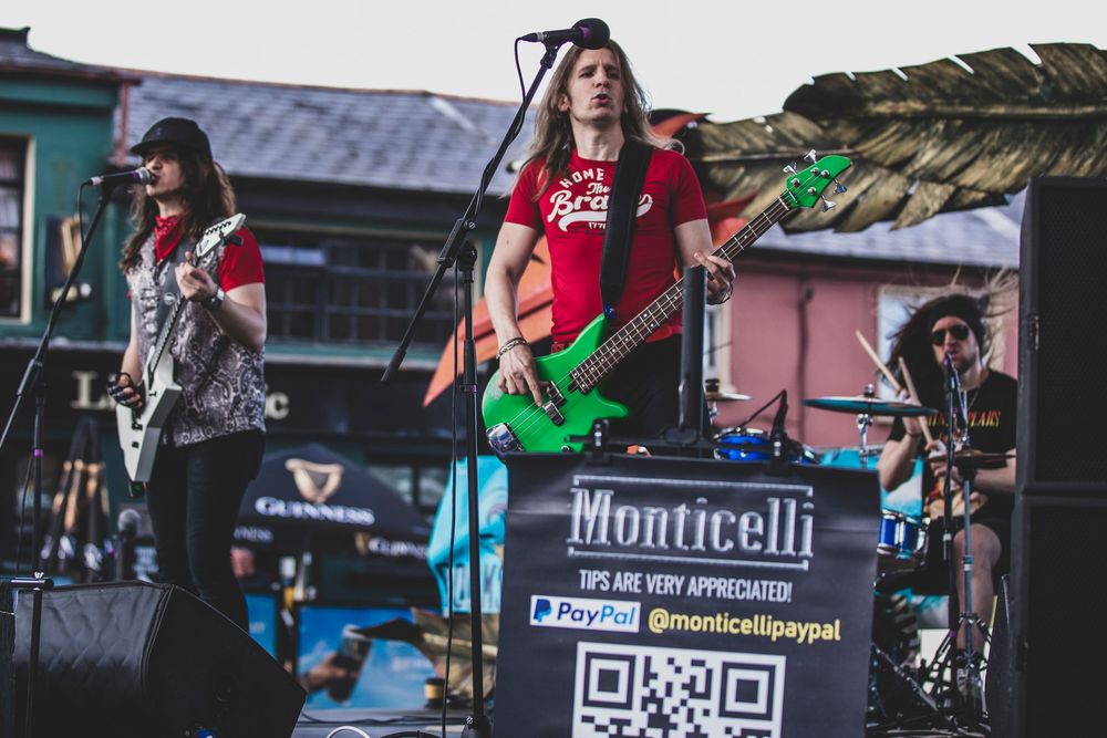 Musicians perform on stage with guitars and instruments during a live concert at an outdoor venue.