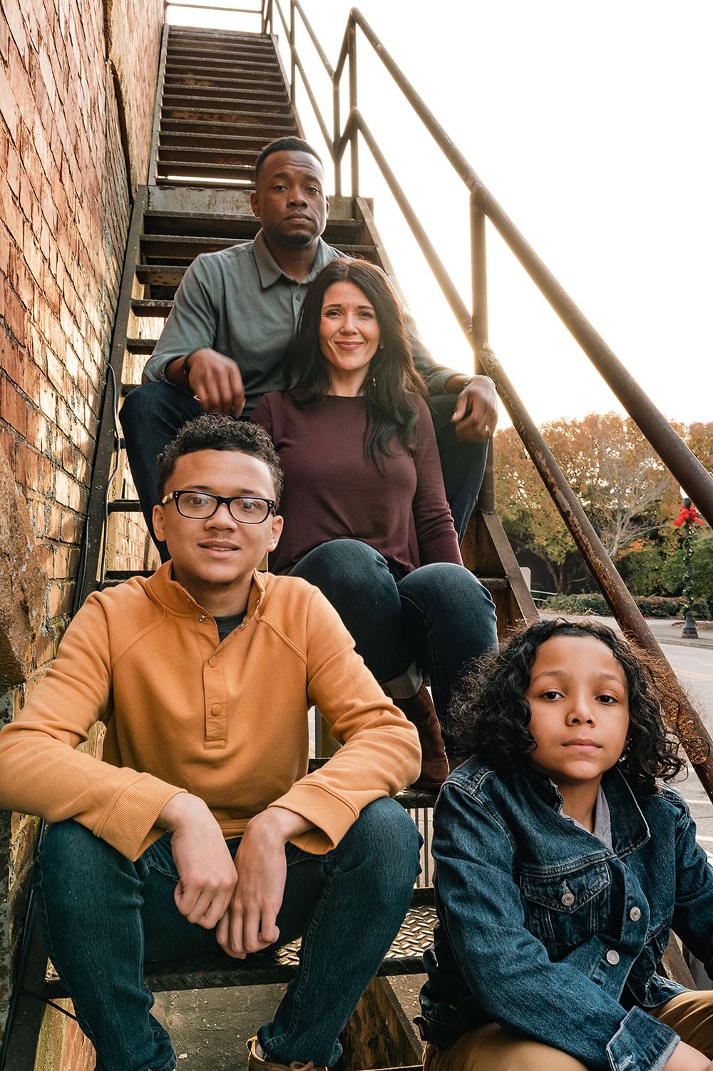 A family poses on metal stairs against a brick wall outdoors.