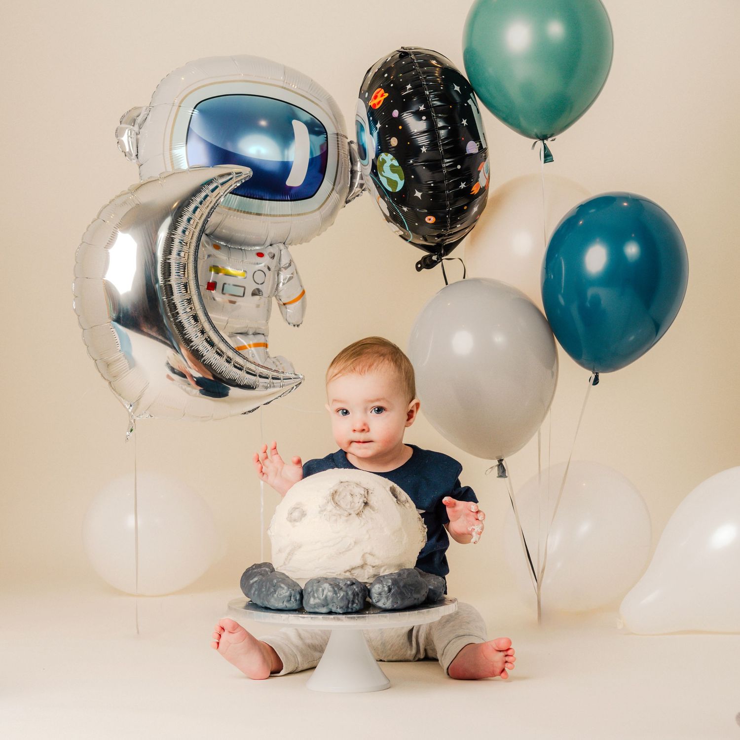 A first birthday photo series with festive balloons in teal, silver, and black colors against a neutral background.