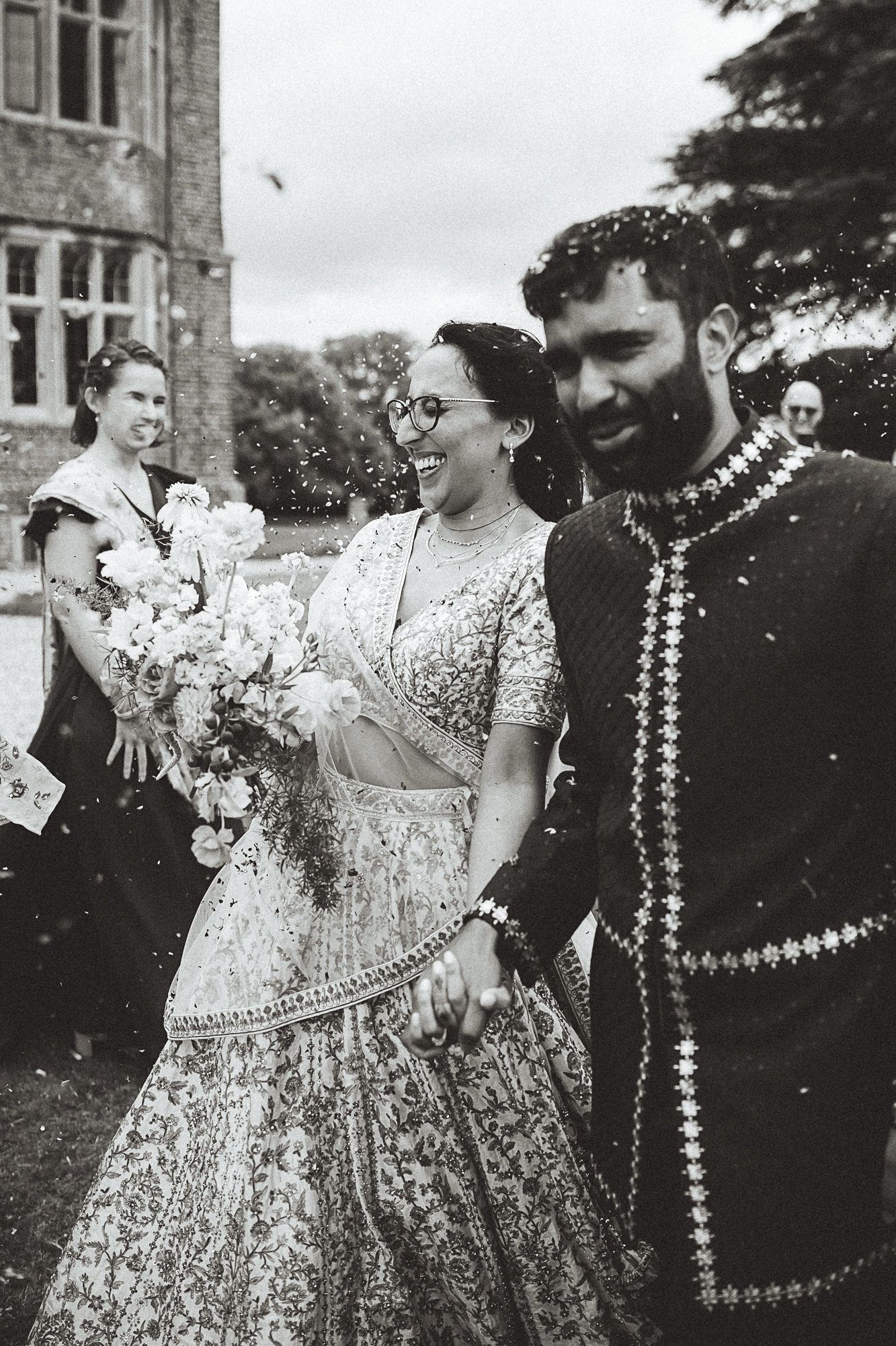 Two people share a warm embrace while one holds a clear umbrella, with genuine smiles and joy visible on a cloudy day.