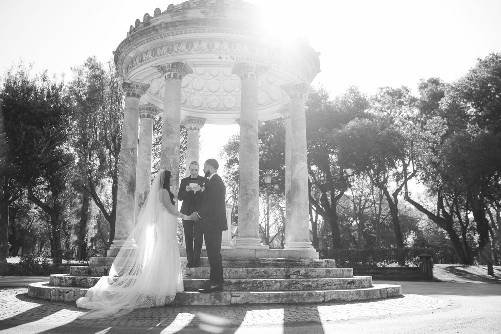 A sunlit wedding ceremony under a grand marble gazebo with architectural details.