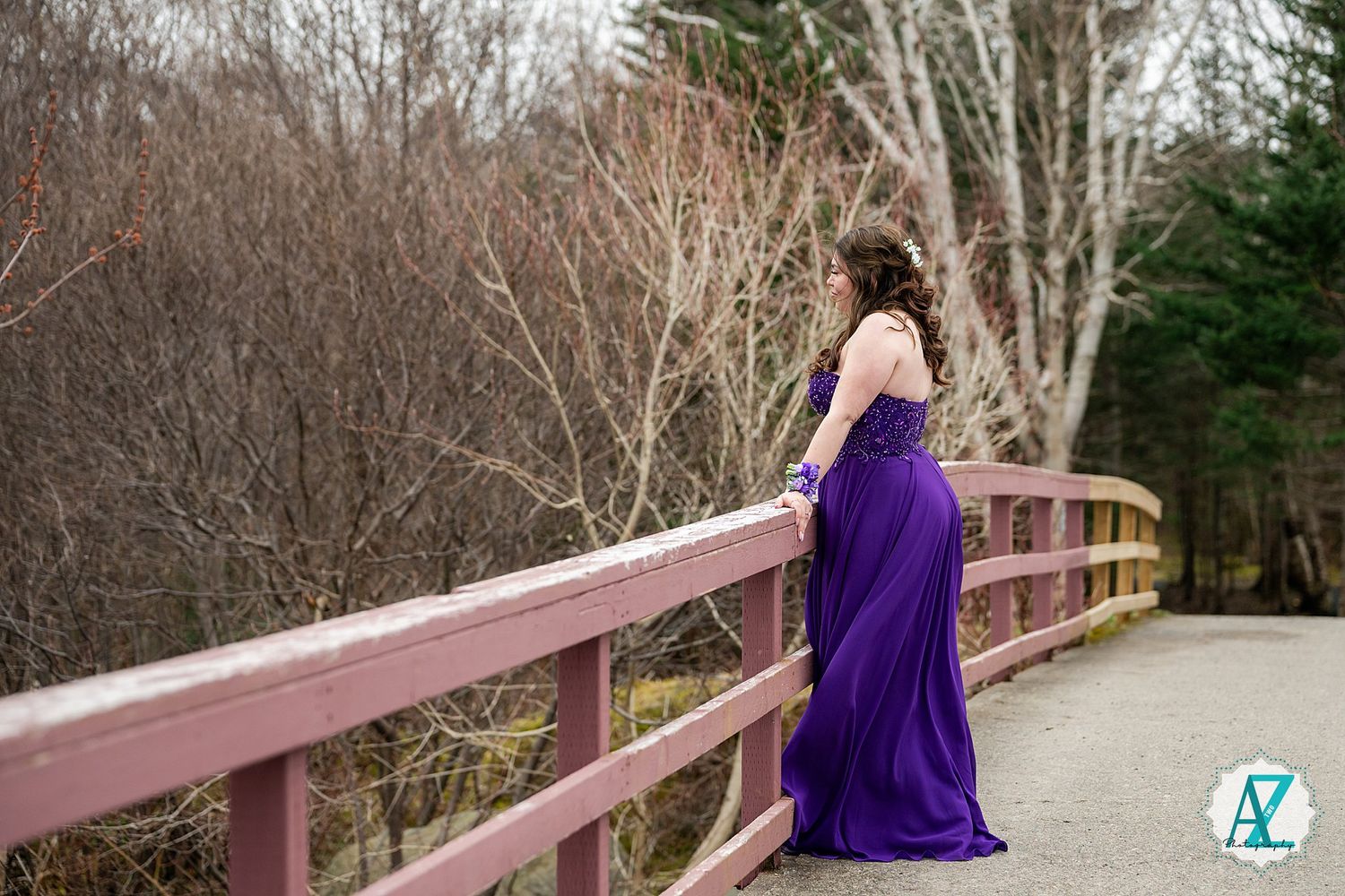 A captivating purple dress stands out against a wooden bridge surrounded by winter bare trees.