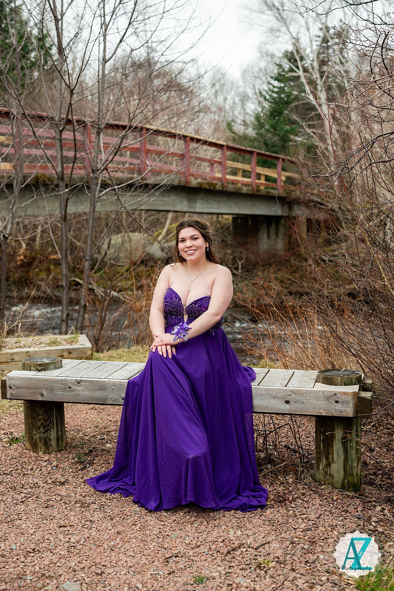 A purple ball gown contrasts beautifully with a rustic wooden bridge and autumn forest scene.