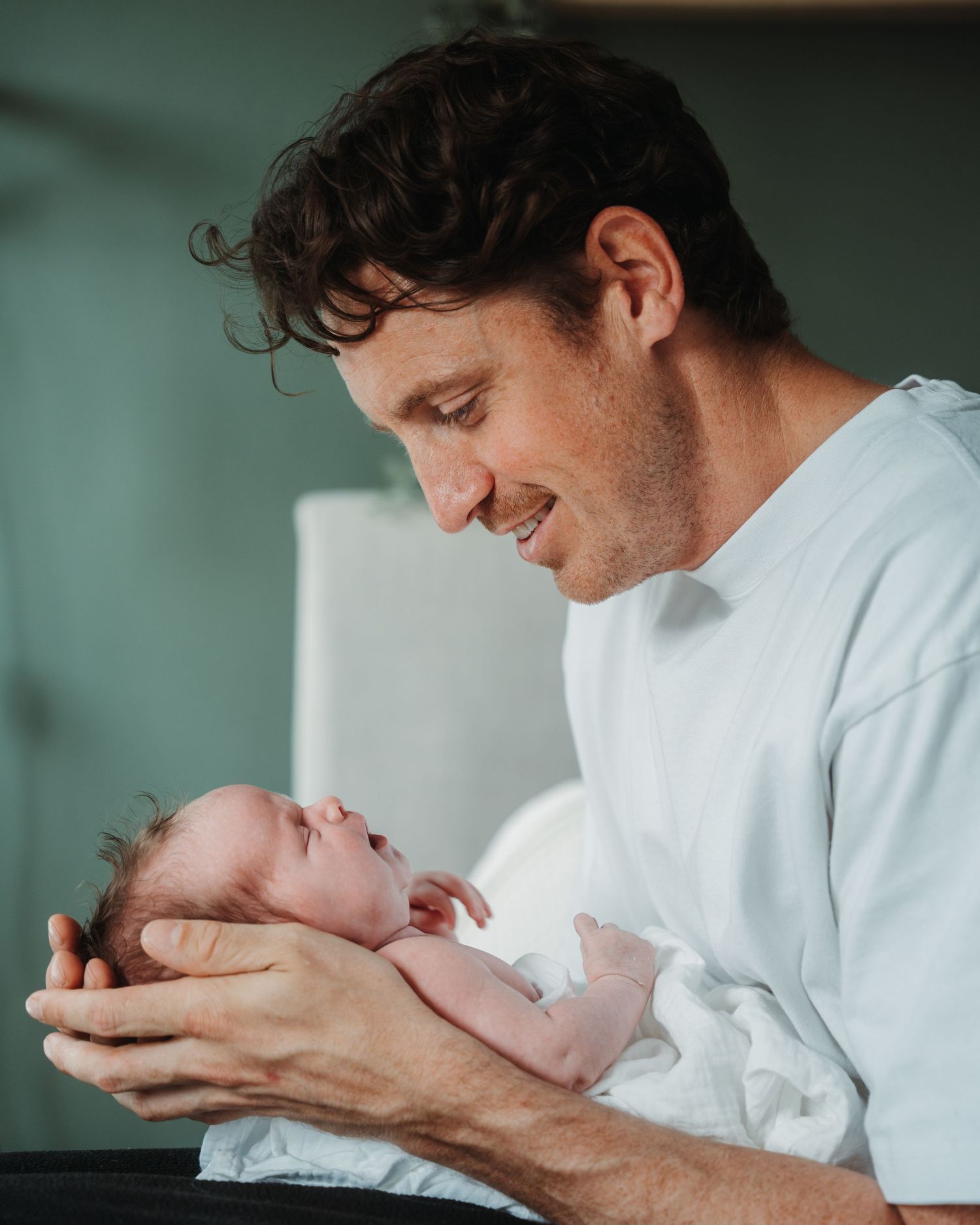 Tender moment as parent cradles newborn baby while smiling warmly.