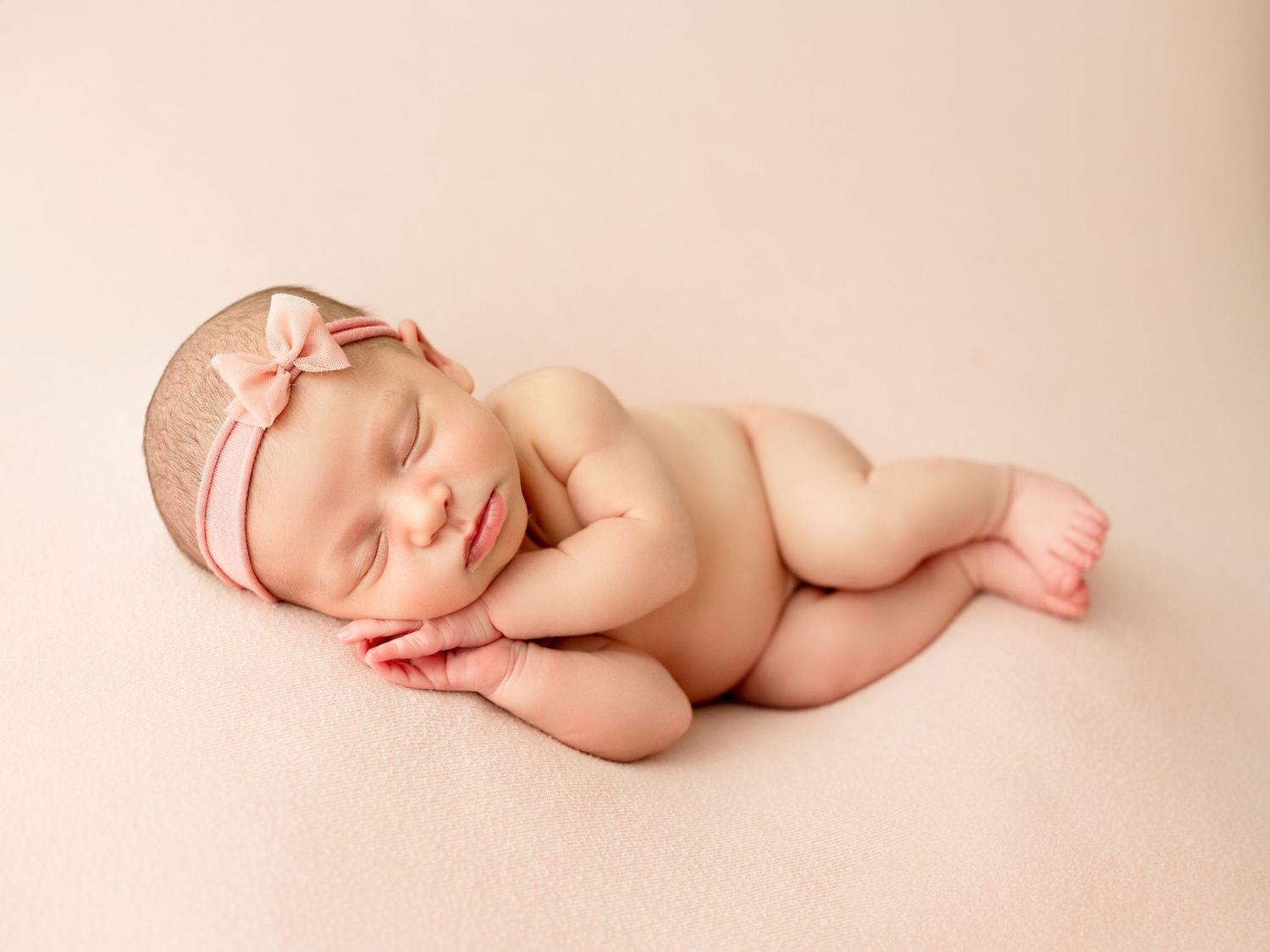 An infant peacefully sleeping while wrapped in a soft beige blanket.