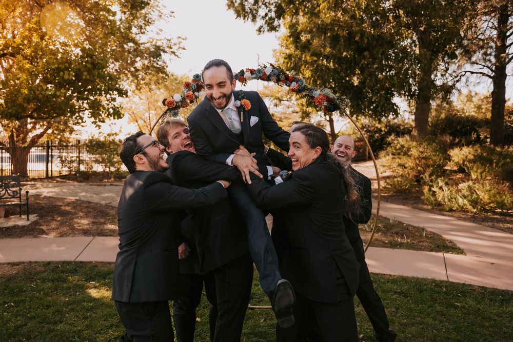 Five groomsmen lift up the groom in celebration. Small weddings in New Mexico. Intimate wedding venues. Albuquerque Garden Center weddings.