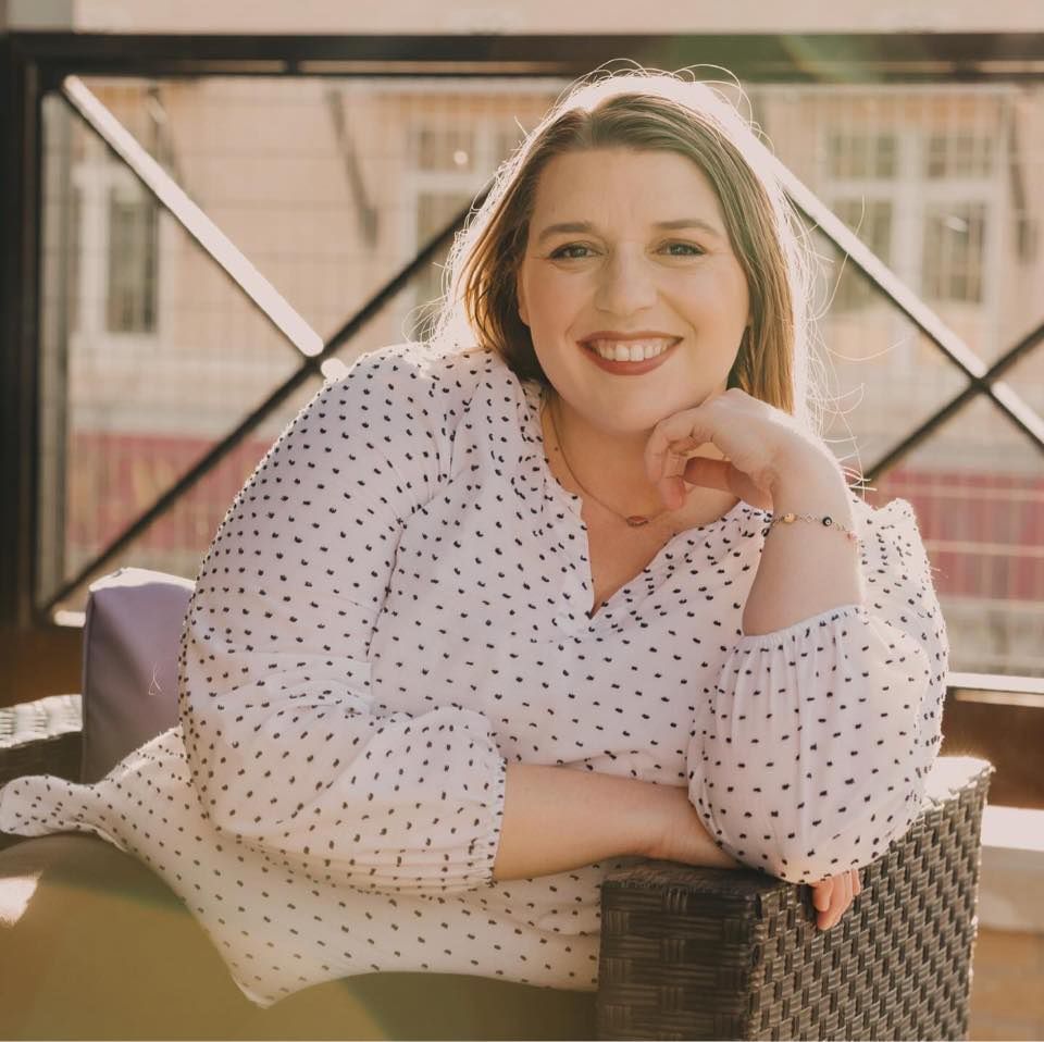 Person in polka dot dress poses casually on outdoor patio with warm vintage-style lighting.