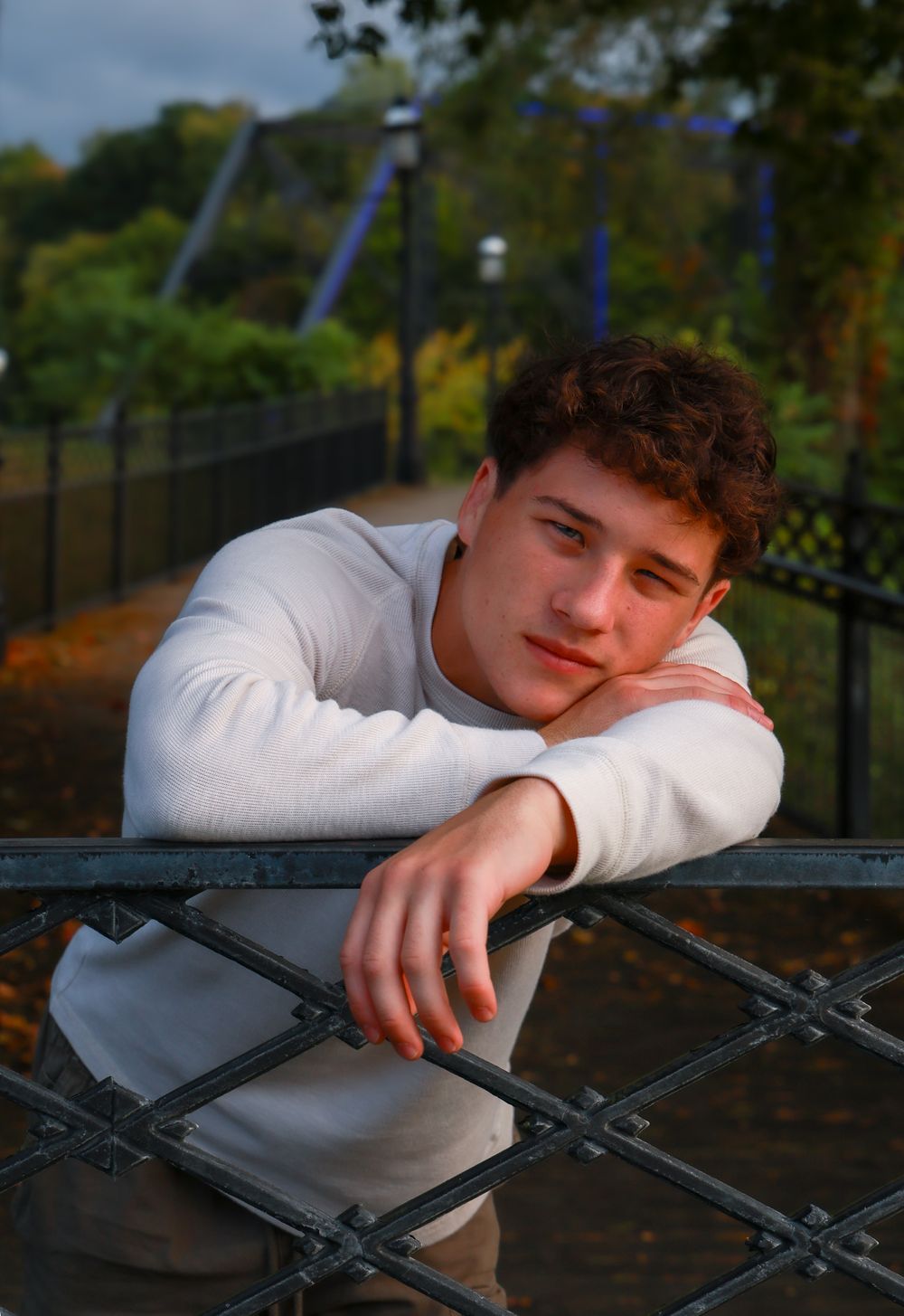 Person in white sweater rests on metal railing during golden hour.