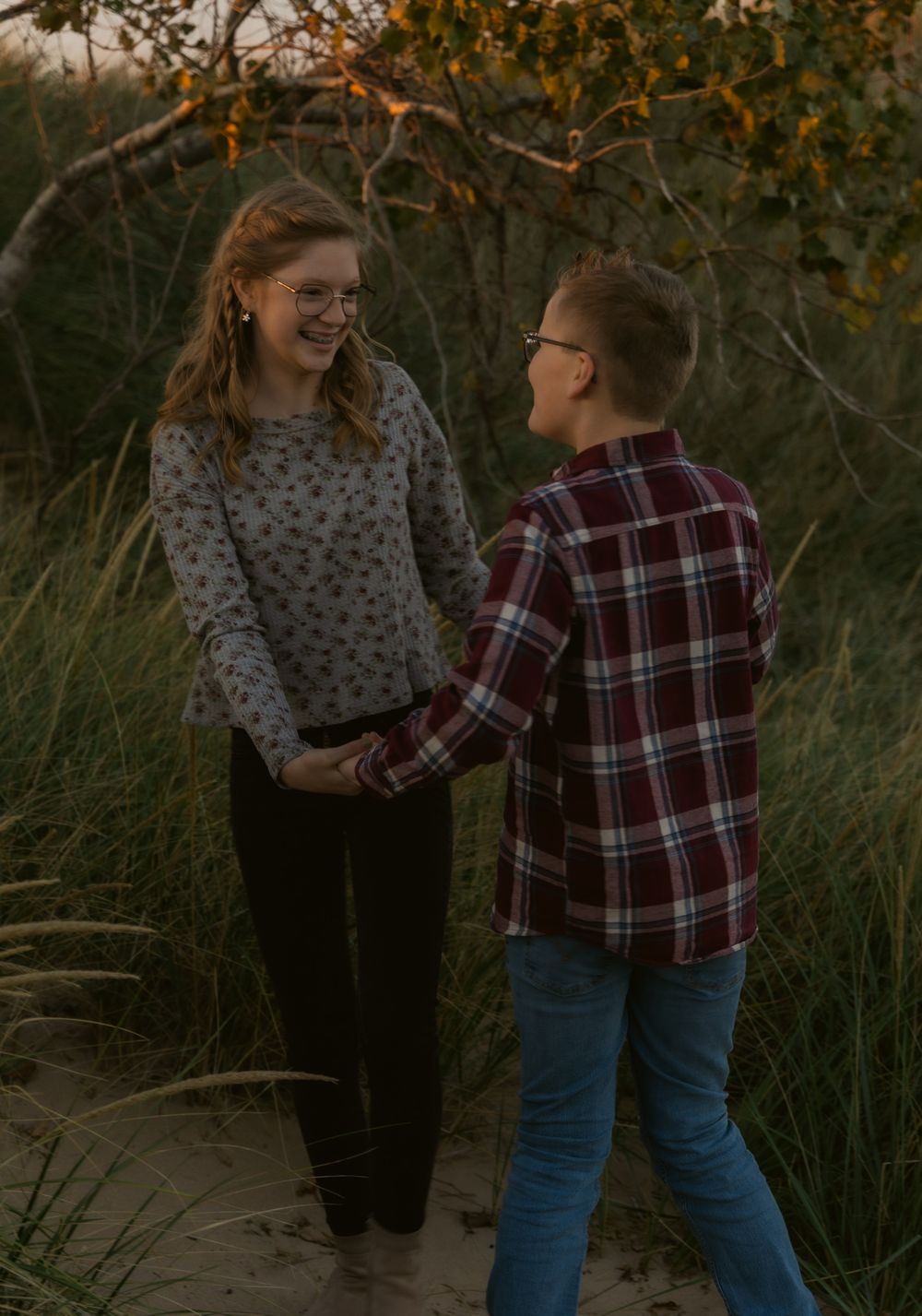 Two people in casual attire share a sweet moment together during golden hour in a natural outdoor setting.