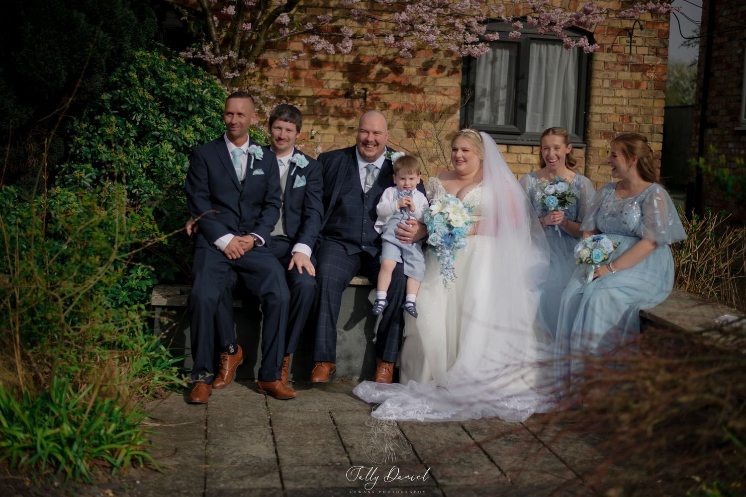 Creative wedding photograph showing a couple peeking through white sheer veil fabric against a brick wall backdrop.