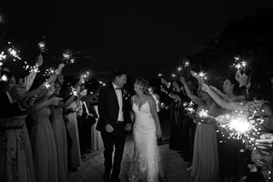 Bride and groom exit through a sparkler tunnel surrounded by wedding party in black and white photo, at Brantview in St. George.