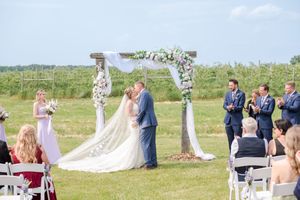 Bride and groom share first kiss at outdoor wedding ceremony beneath a floral decorated wooden arch, at Brantview in St. George.