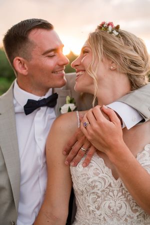 Bride and groom smiling intimately at golden hour sunset, bride wearing floral hair accessories, at Brantview in St. George.