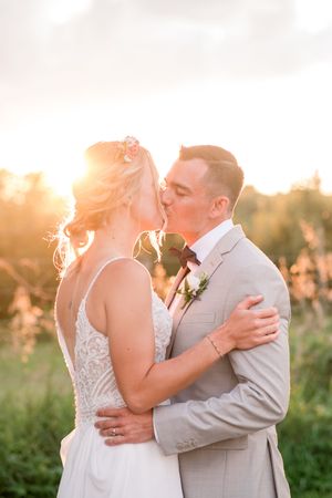 Bride and groom share a romantic golden hour kiss outdoors with warm sunset light glowing behind them at Brantview in St. George.