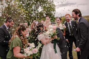Wedding party celebrates newlyweds with confetti toss outdoors in joyful group photo, In Paris, Ontario.