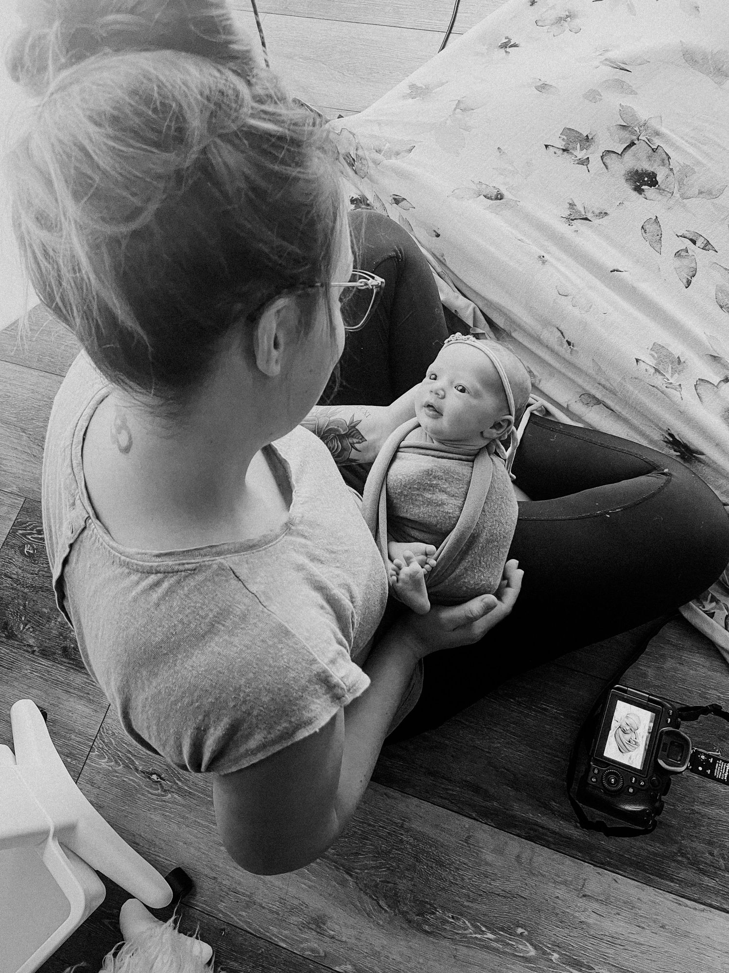 A tender black &white moment between parent and infant resting on a couch with natural lighting filtering through. MI Newborn Photographer