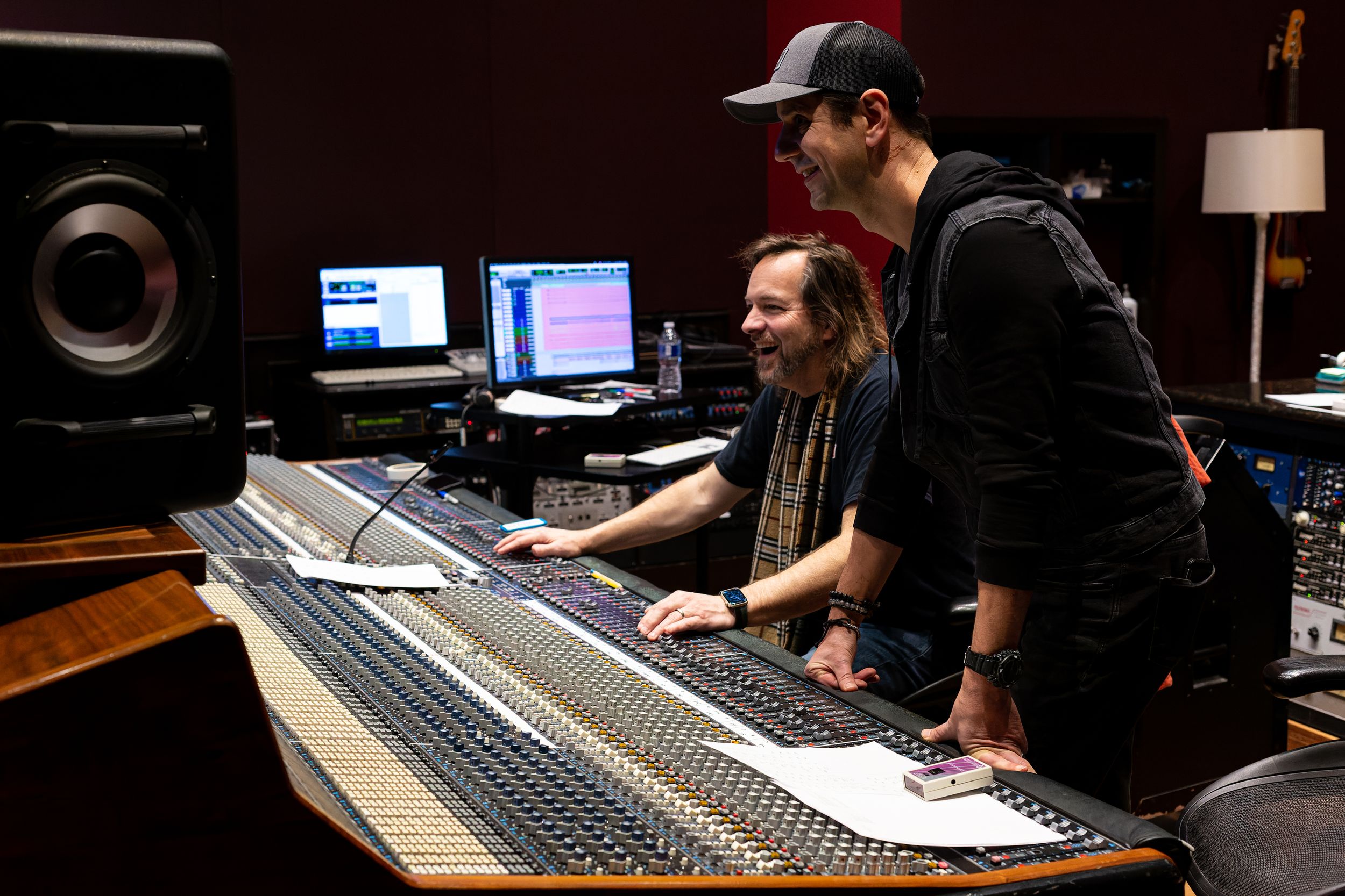 Musicians collaborating at mixing board in professional recording studio. Producer Sal Oliveri