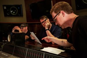 Group reviewing music sheets at recording studio console.