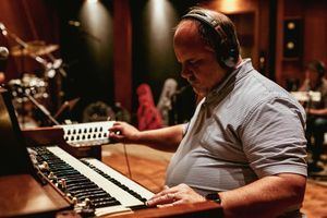 Renowned American gospel singer, songwriter, and pianist Gordon Mote playing piano in dimly lit recording studio.