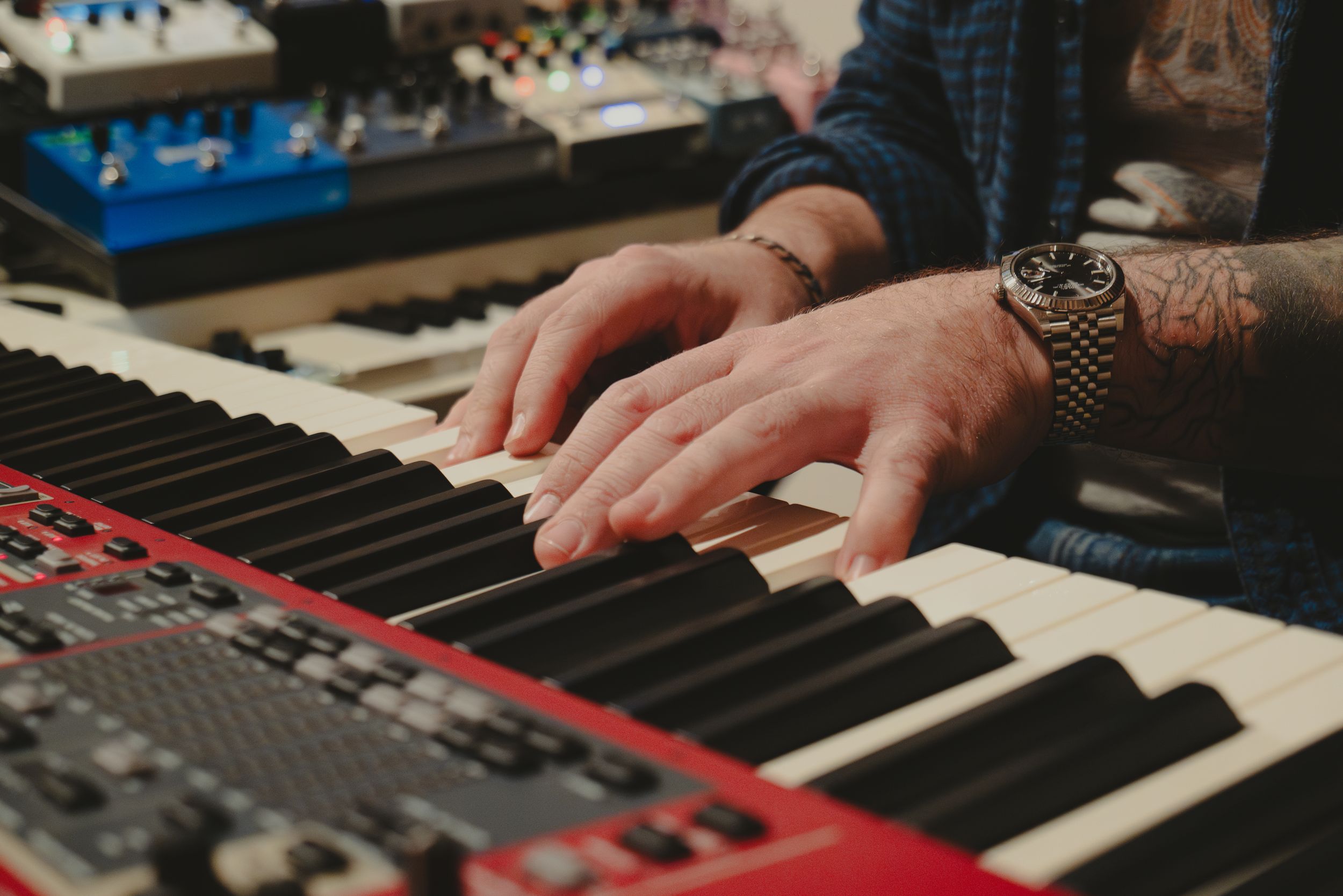 Close-up of hands playing keyboard synthesizer in a recording studio.