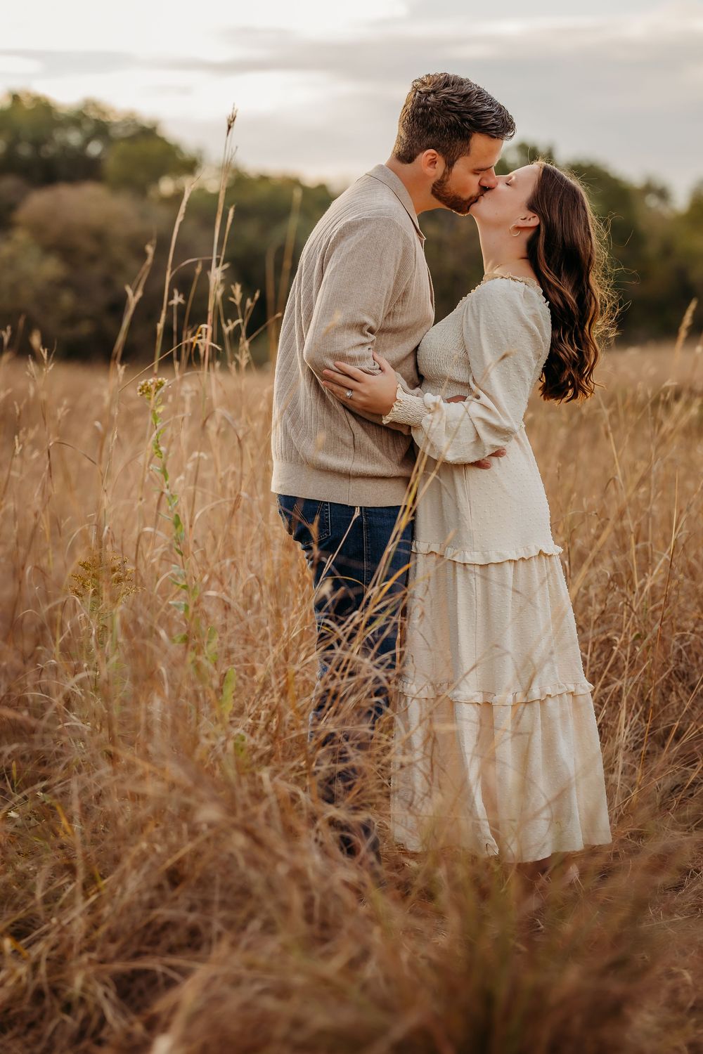 Romantic couple shares tender moments in a golden autumn field at sunset.