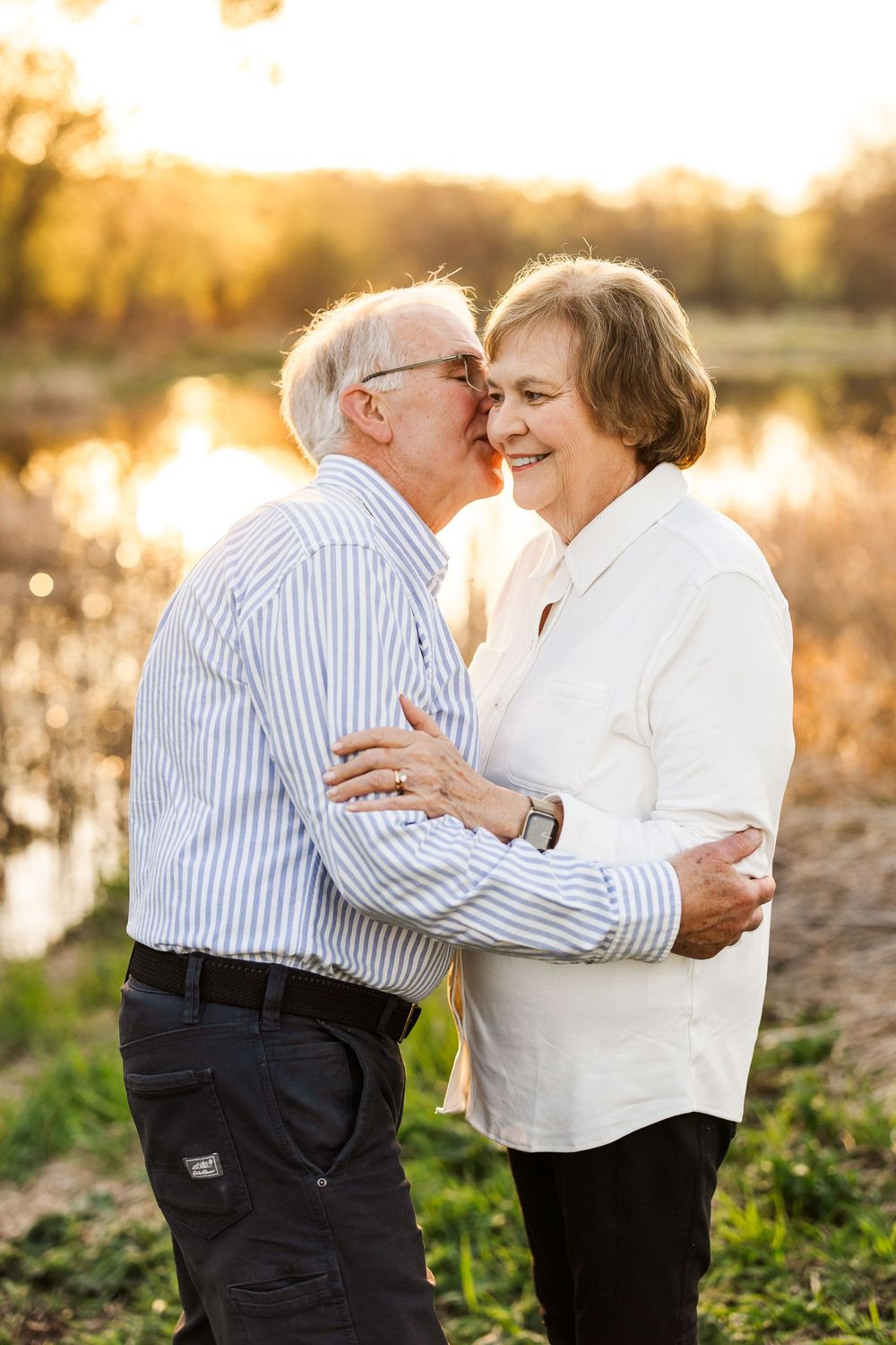 Senior couple sharing an intimate moment together outdoors during golden hour sunset in a natural setting.