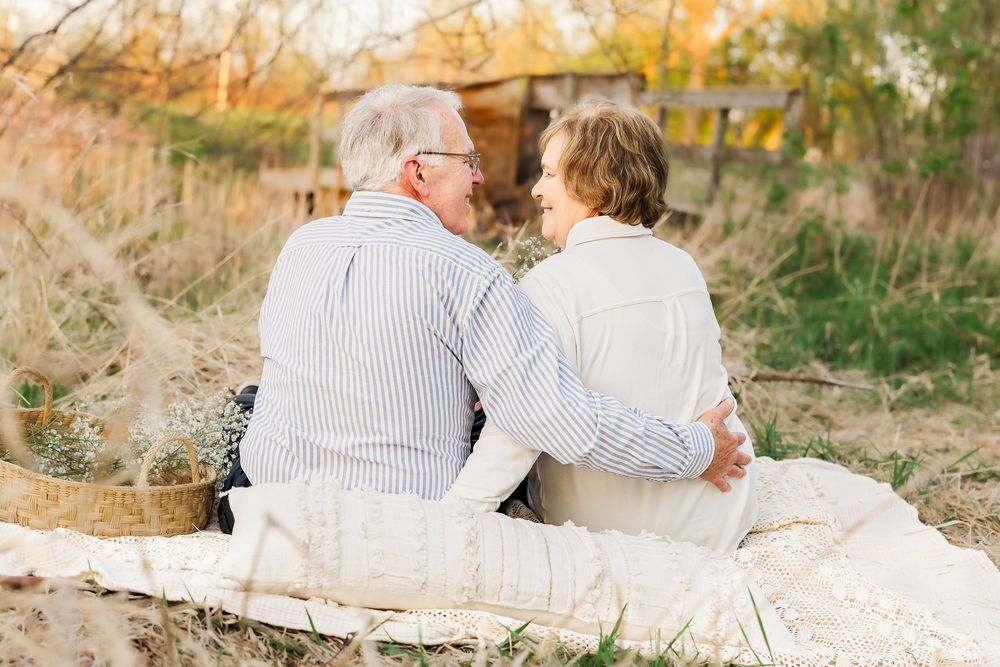 Couple in matching light colored outfits sitting close together outdoors during golden hour sunset.
