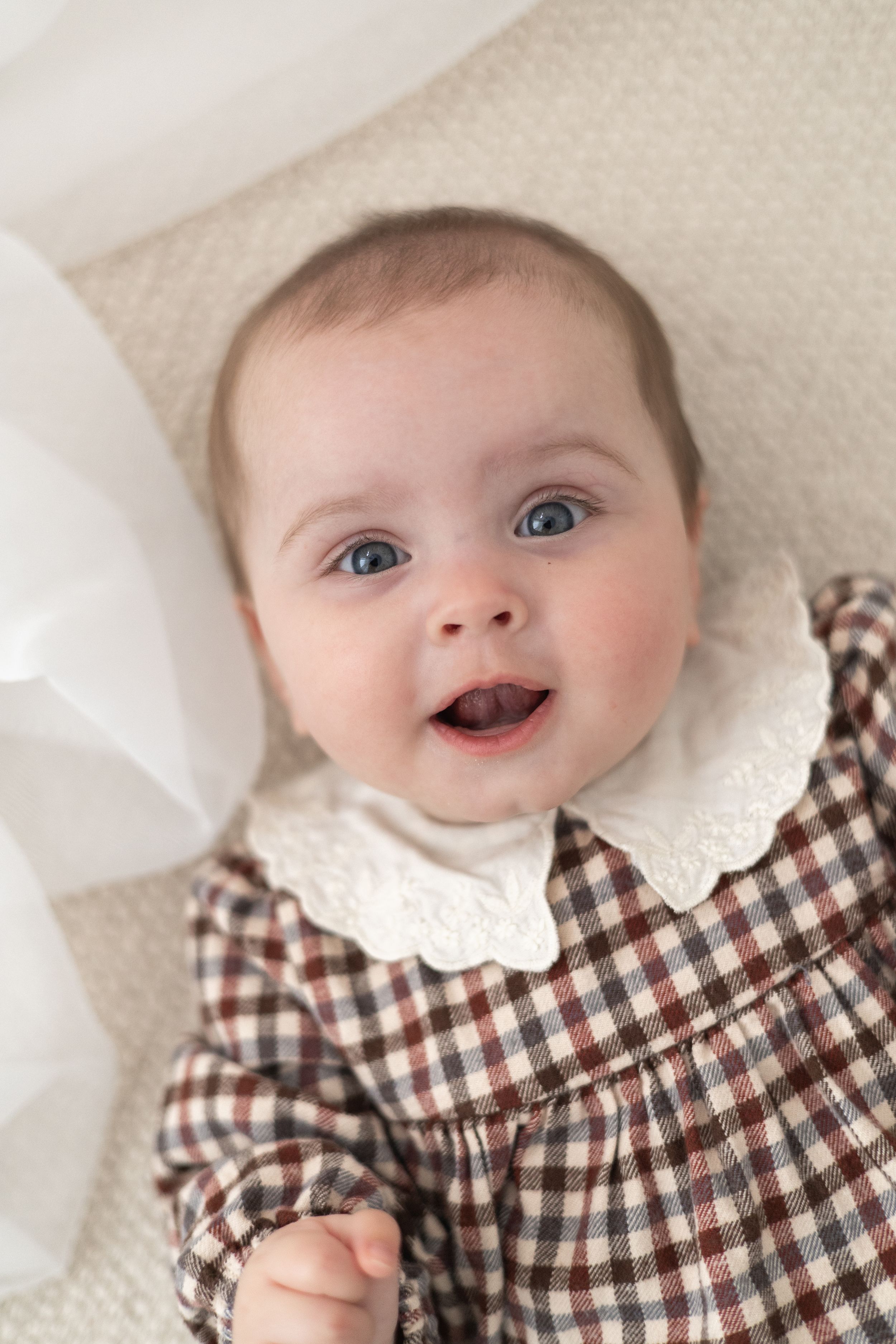 Smiling baby with blue eyes wearing a brown gingham dress baby / milestone birthday photoshoot Nottingham