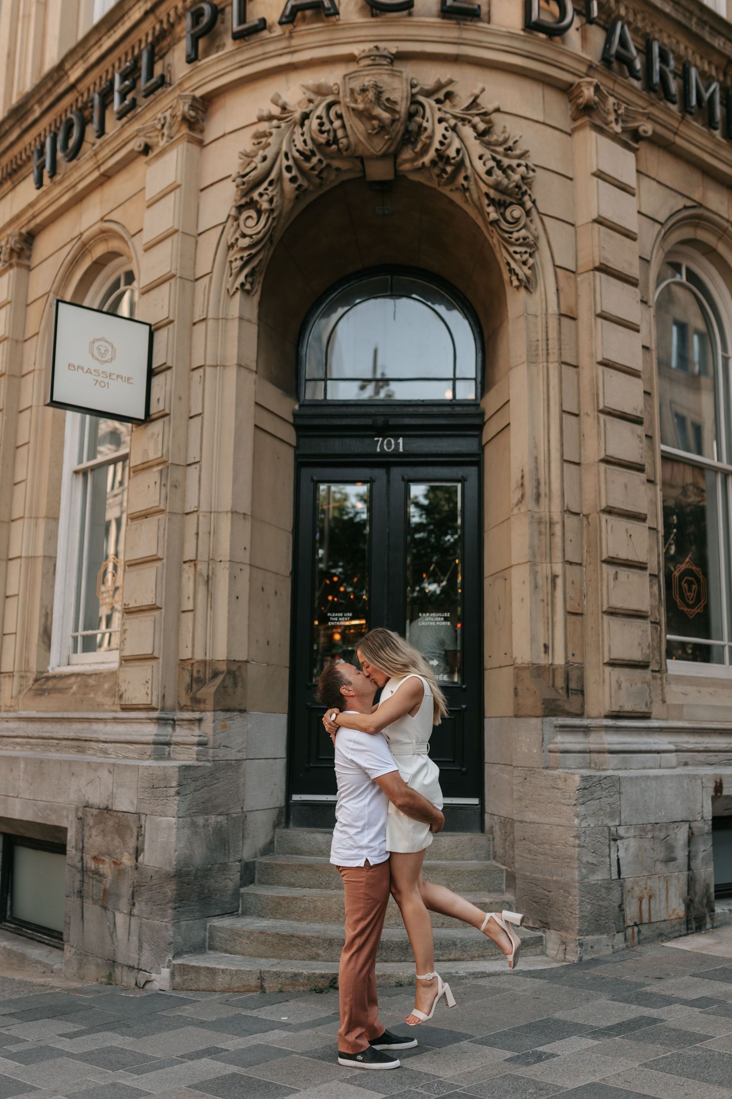 Couple embracing and laughing outside Hotel Place d'Armes historic building entrance at 701.