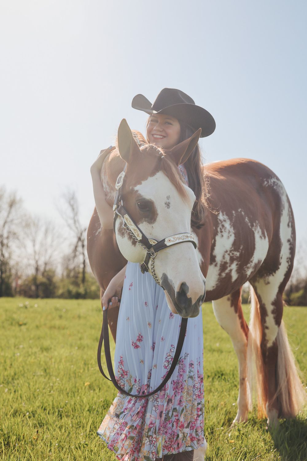 A painted horse and rider share a tender moment in a sunny meadow.