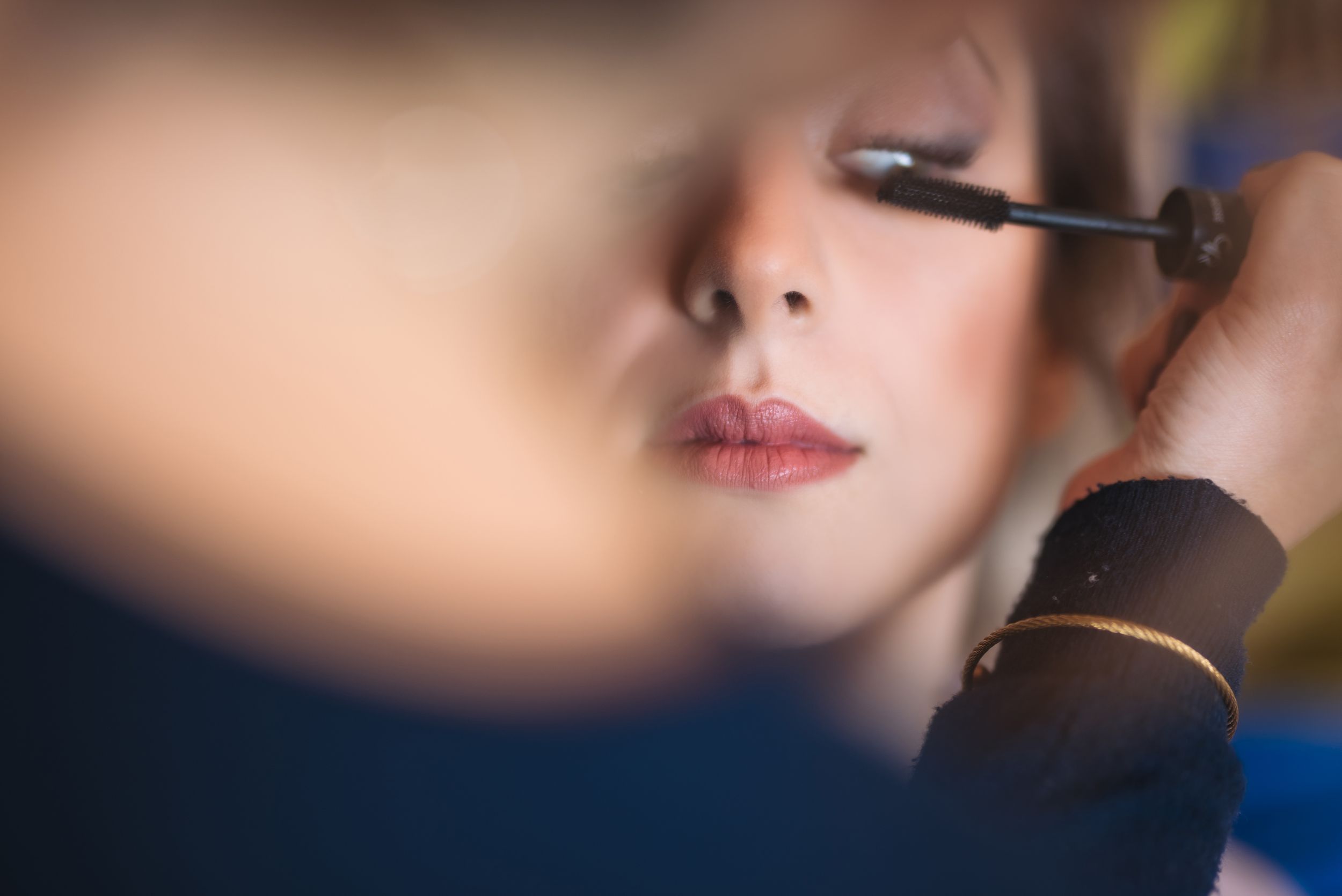Close-up shot of mascara being applied to eyelashes during makeup application.