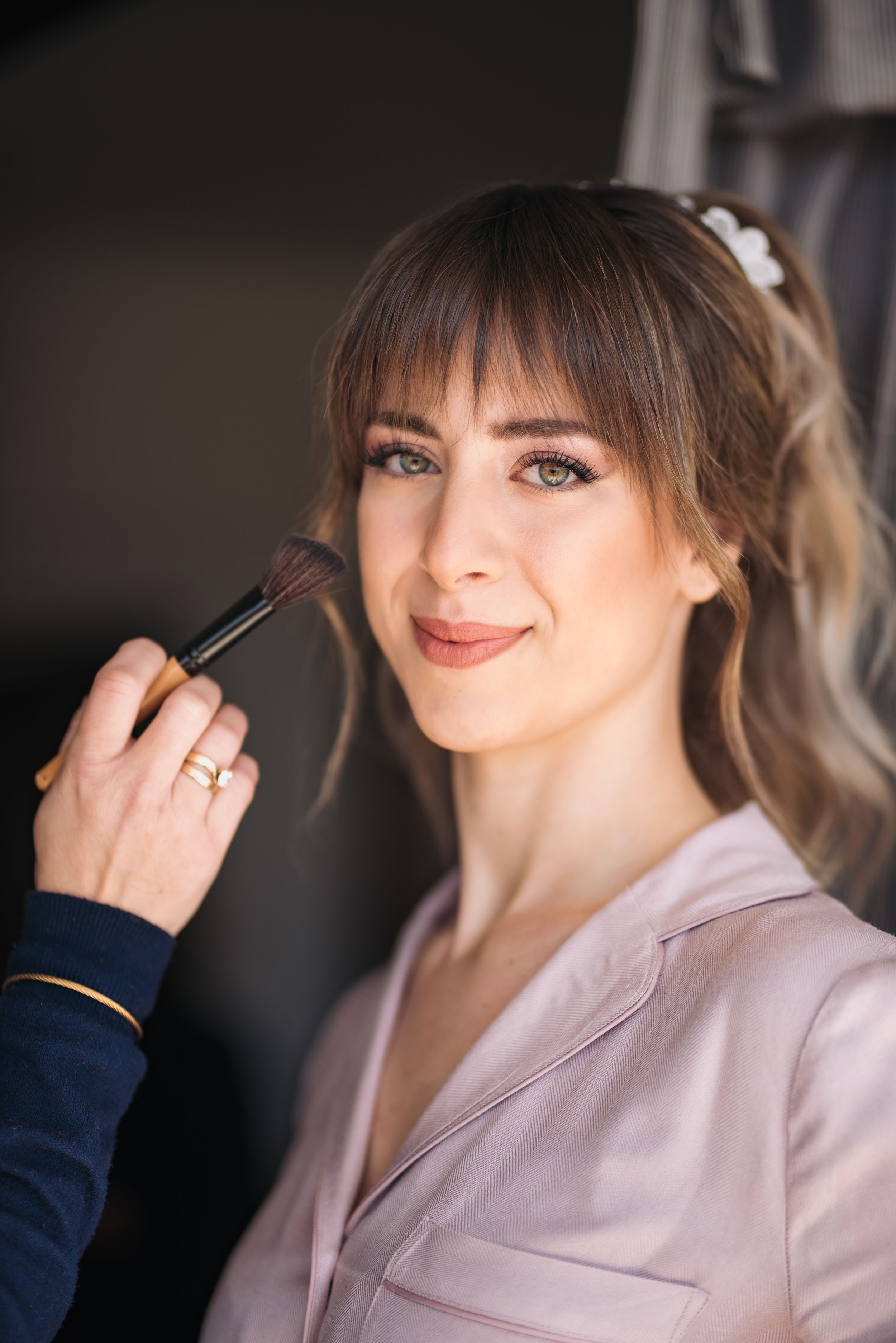 Makeup artist applying finishing touches with a brush during bridal preparation.