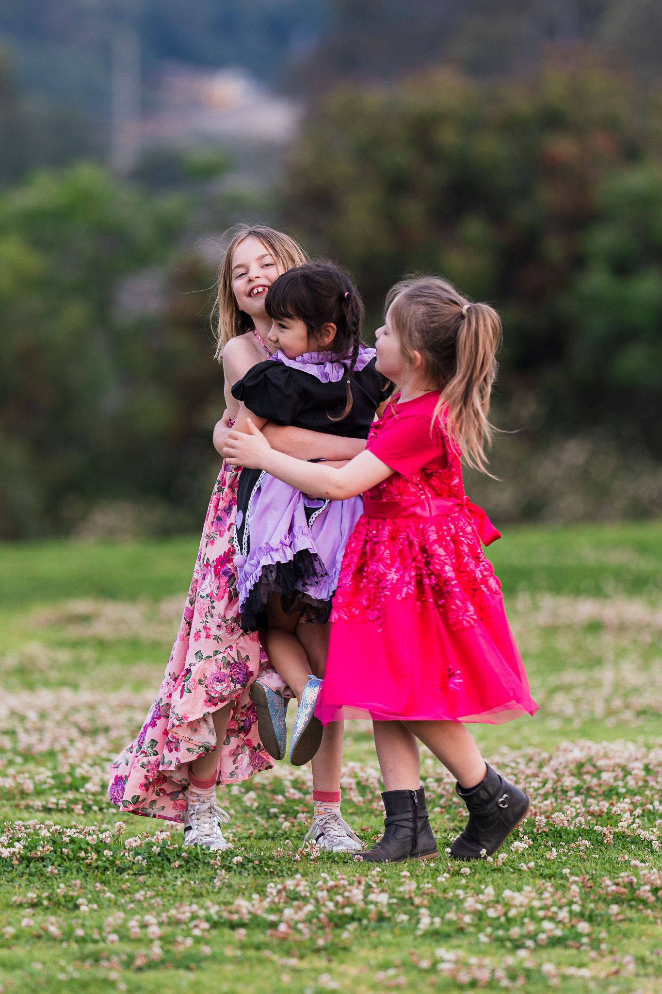 A toddler in a purple bunny sweater and black pants walks across a grassy field on an overcast day.