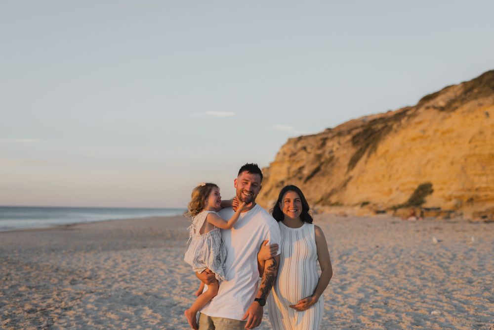 Group walking and laughing together on sandy beach at sunset with golden cliffs in background.