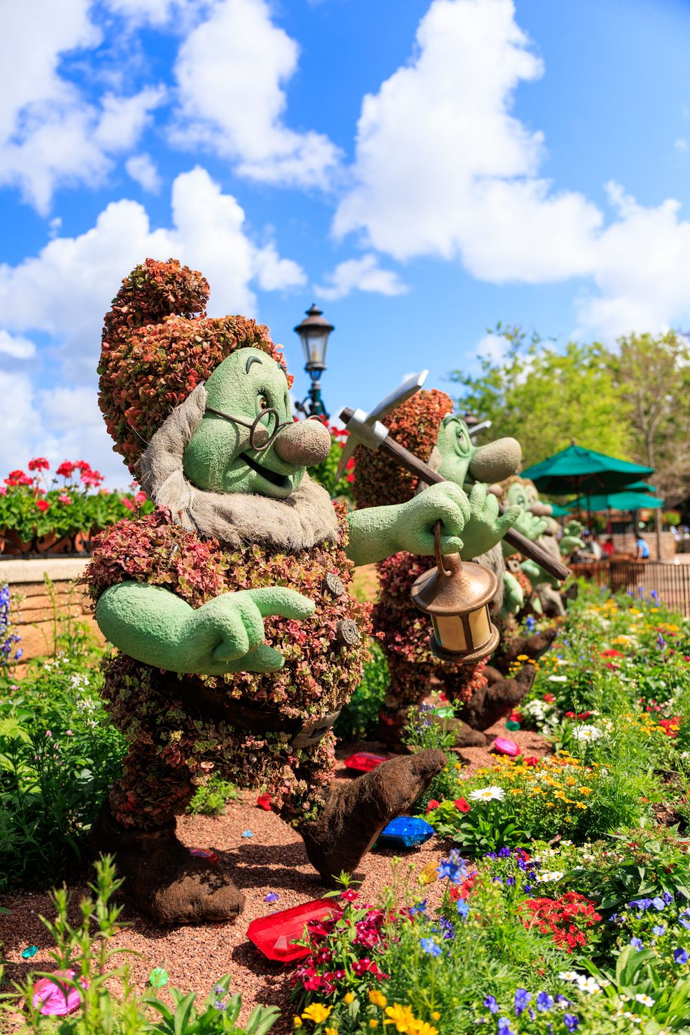 Colorful garden display featuring whimsical topiary characters surrounded by vibrant flowers at Disney World's EPCOT.