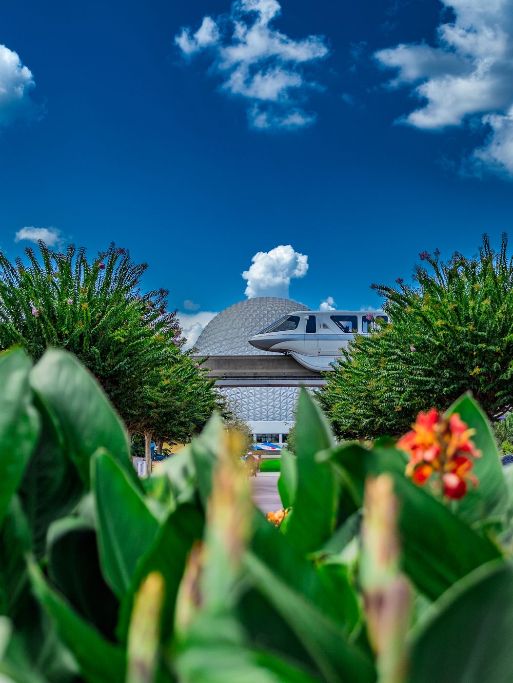 Colorful flowers bloom beneath Spaceship Earth's distinctive geodesic dome at EPCOT.