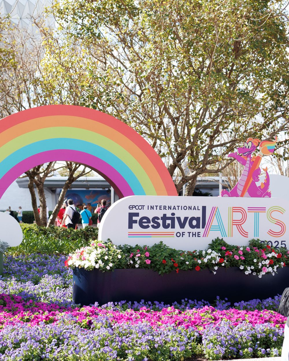 Colorful rainbow arch display with flowers at EPCOT International Festival of the Arts entrance.