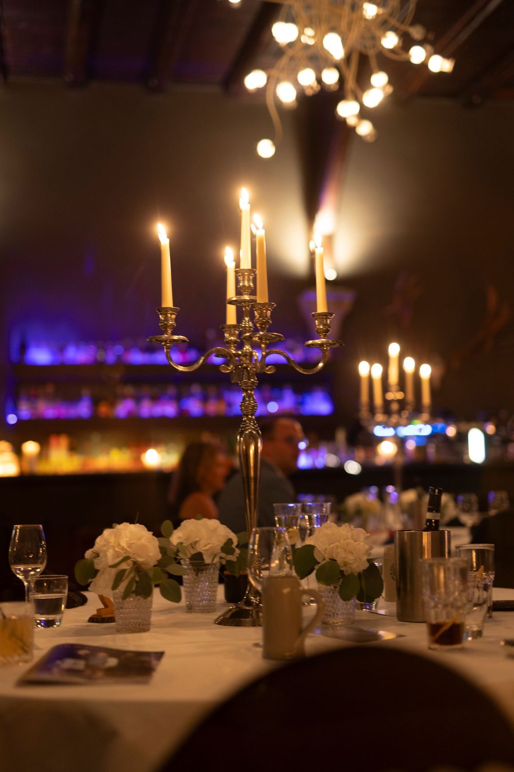 Elegant wedding reception tables set with candelabras and soft lighting.