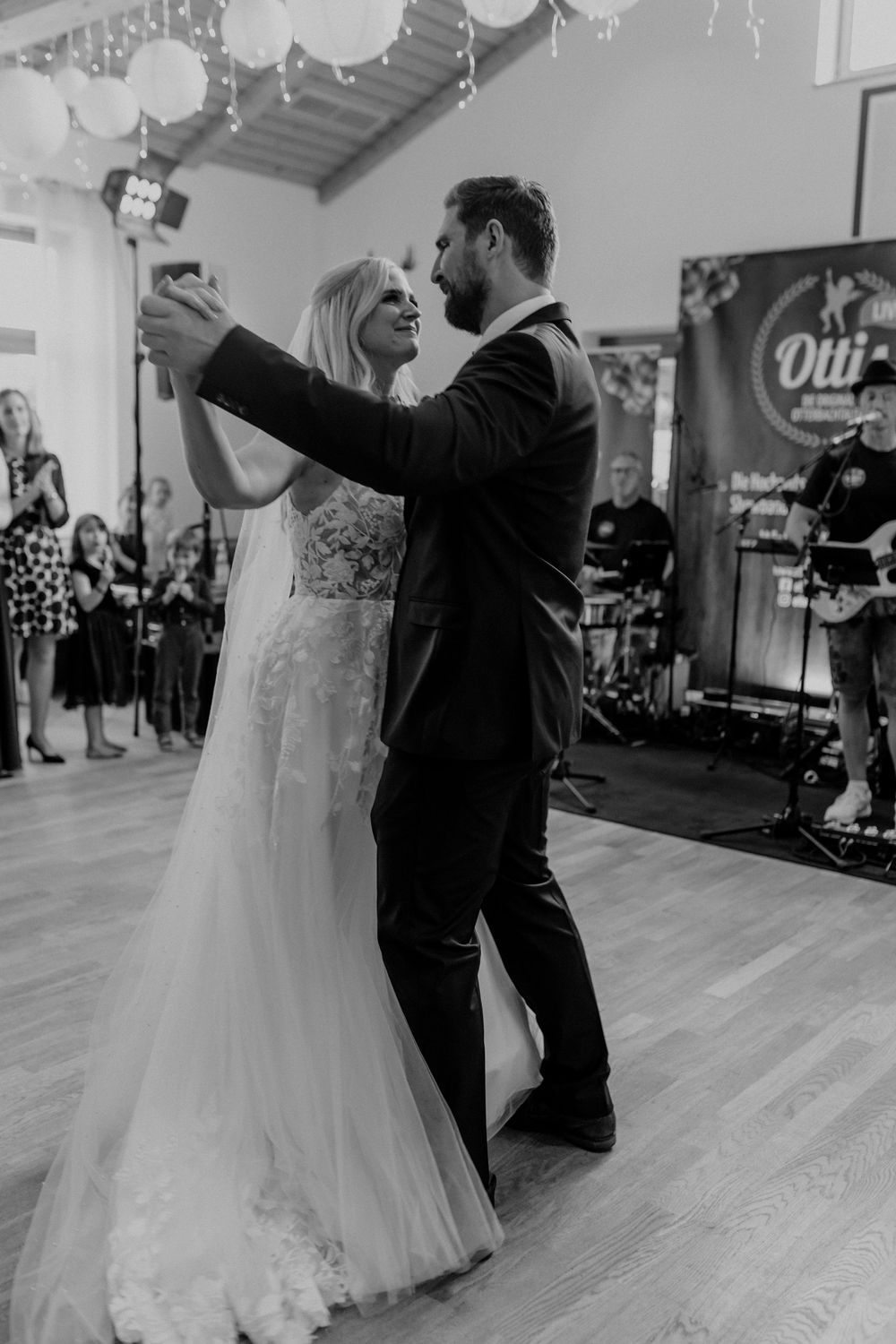 A couple shares their first dance at their wedding reception on a wooden dance floor.