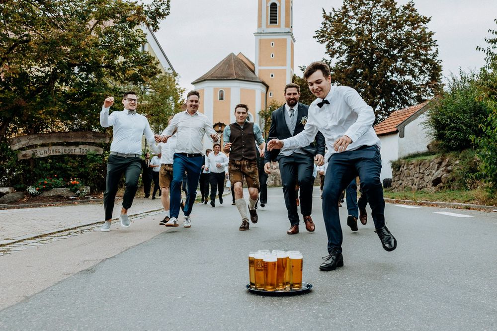 Wedding party running and celebrating on a street with a church in the background.