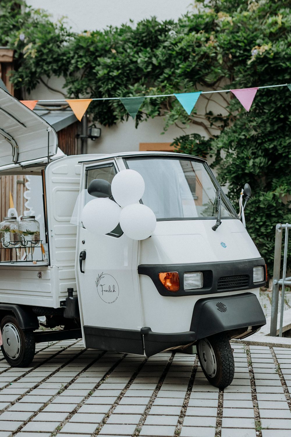 Vintage white vehicles decorated for a wedding with bunting and balloons.