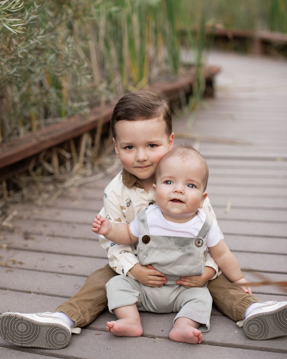 A series of candid shots showing a baby sitting on a wooden boardwalk surrounded by natural scenery.