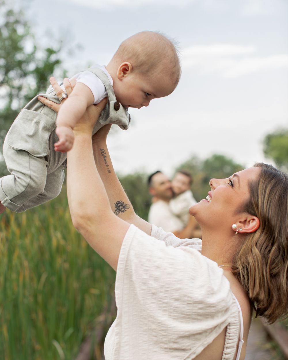 A tender moment between parent and child playing together outdoors with cattails in the background.