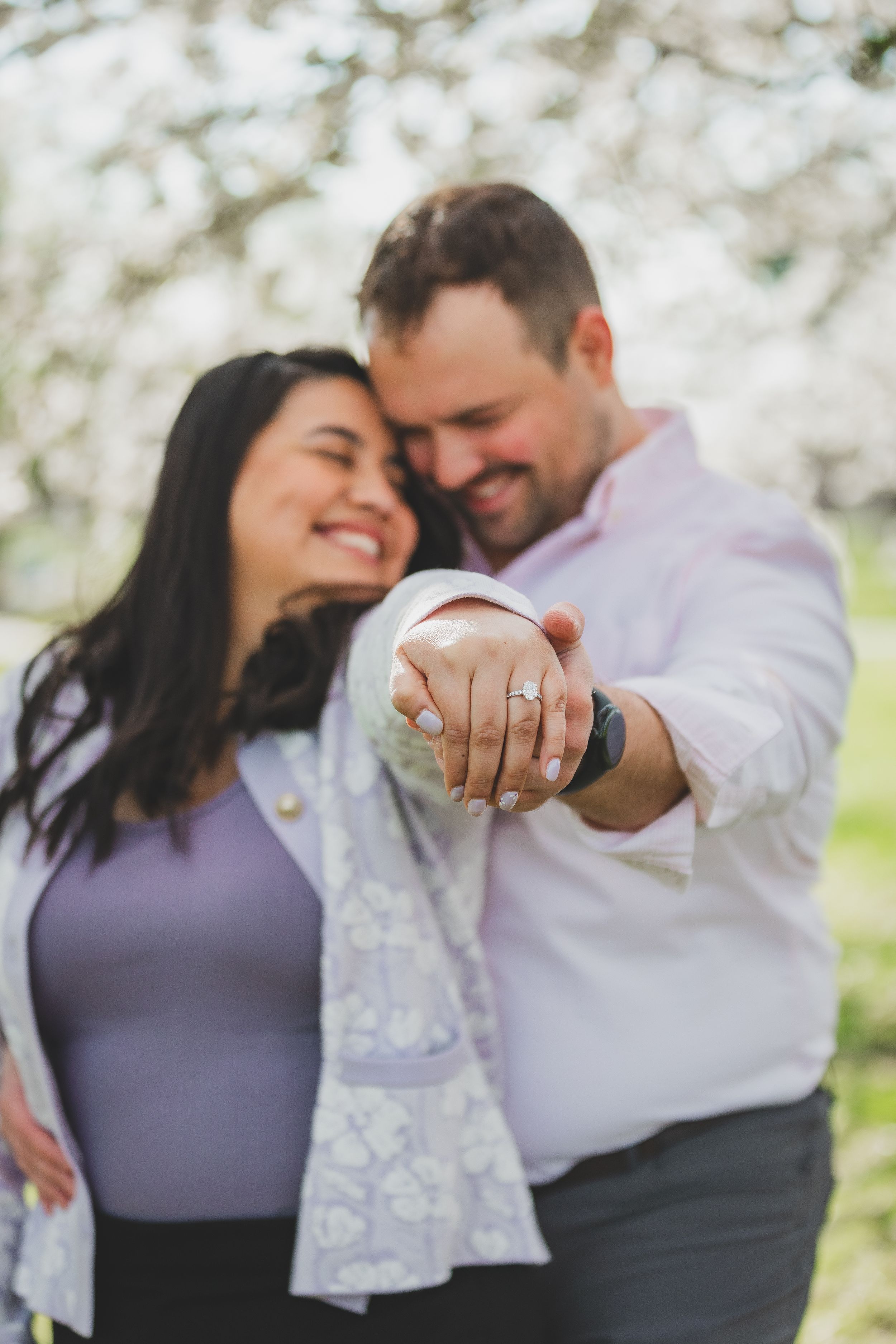 A romantic couple shares intimate moments in a spring orchard with white blossoms at the East Potomac
