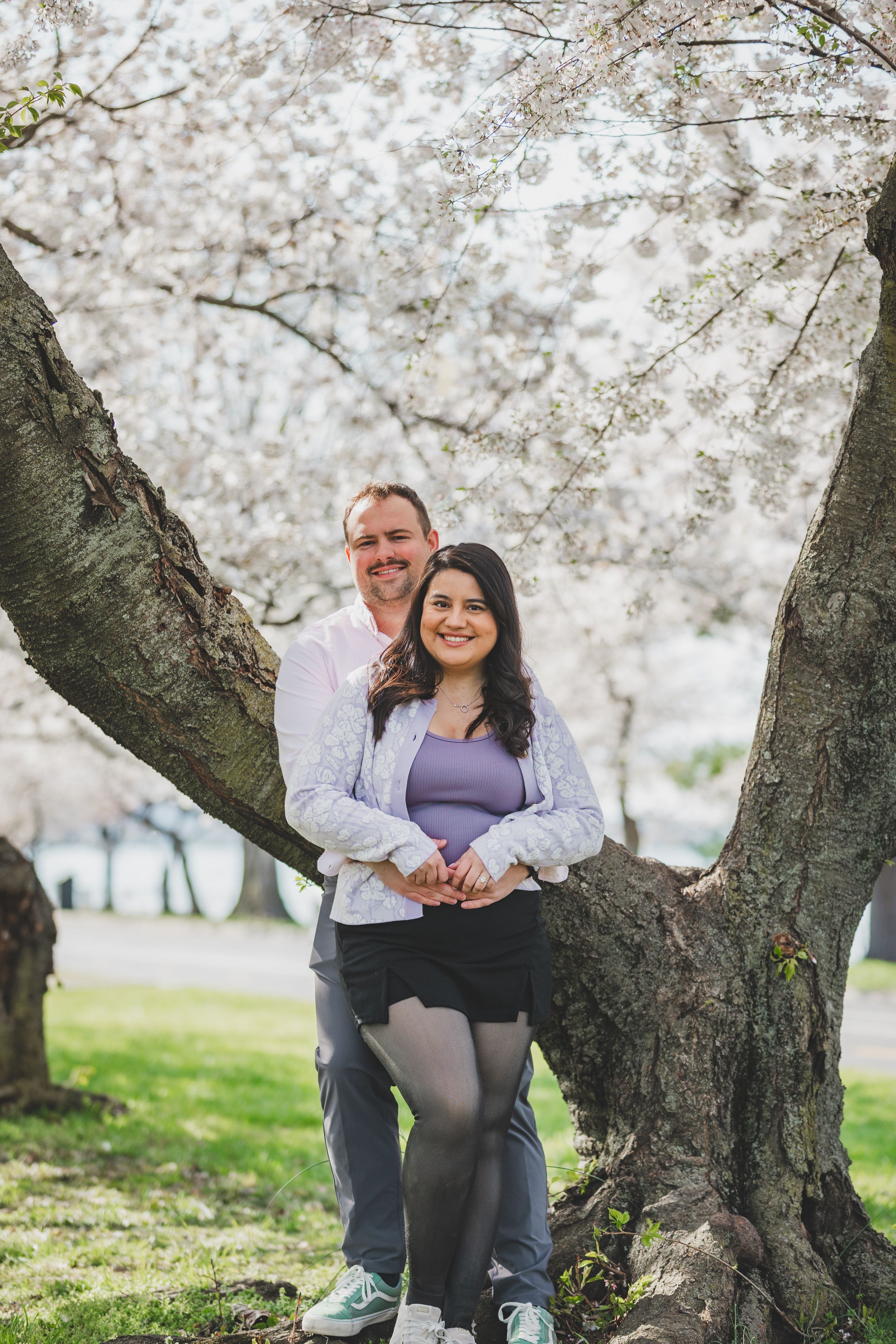 A couple shares a joyful moment under blooming cherry blossom trees on a spring day.
