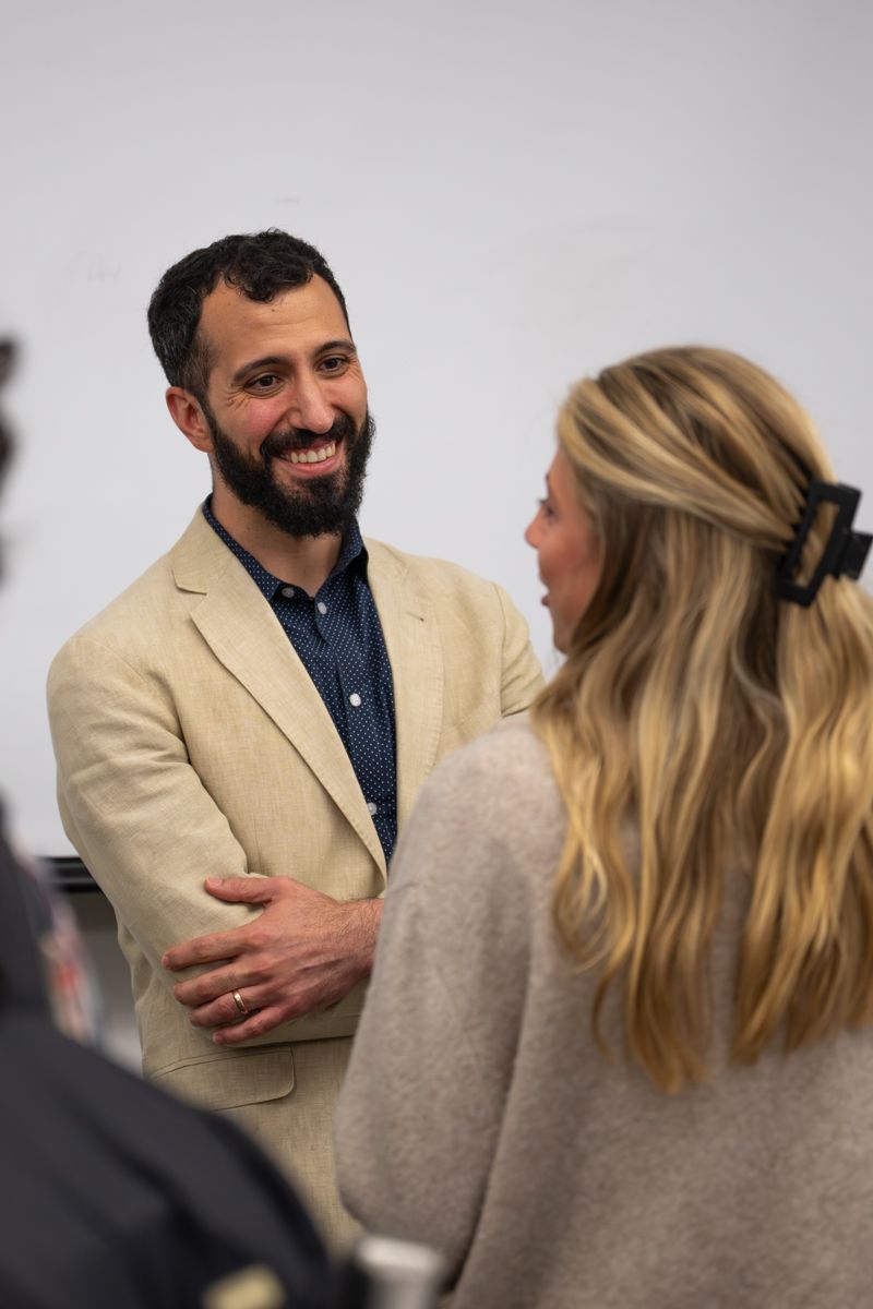 Two people engaged in an animated conversation while standing together in a professional setting.
