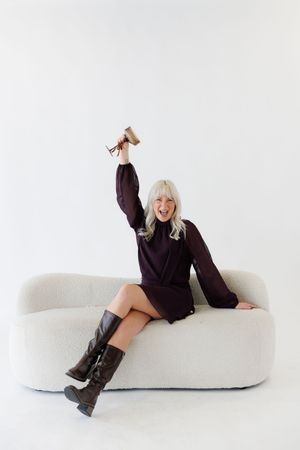 Playful poses on white contemporary furniture in minimalist studio setting with black outfit and boots.
