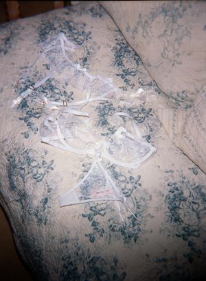 White lace ribbons arranged on a blue and cream floral patterned fabric surface.