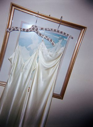 White wedding dresses hanging on hangers against a light wall.